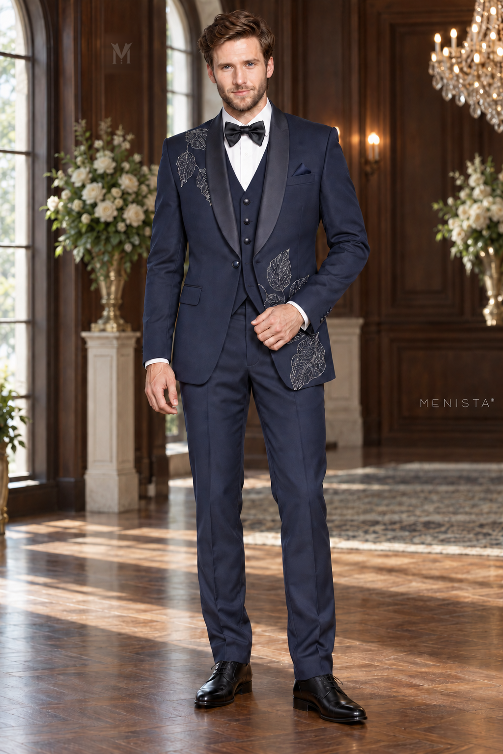 Jack wearing Menista Sylvan navy three-piece tuxedo with silver leaf embroidery and satin shawl lapels, full front view in a wedding ballroom.
