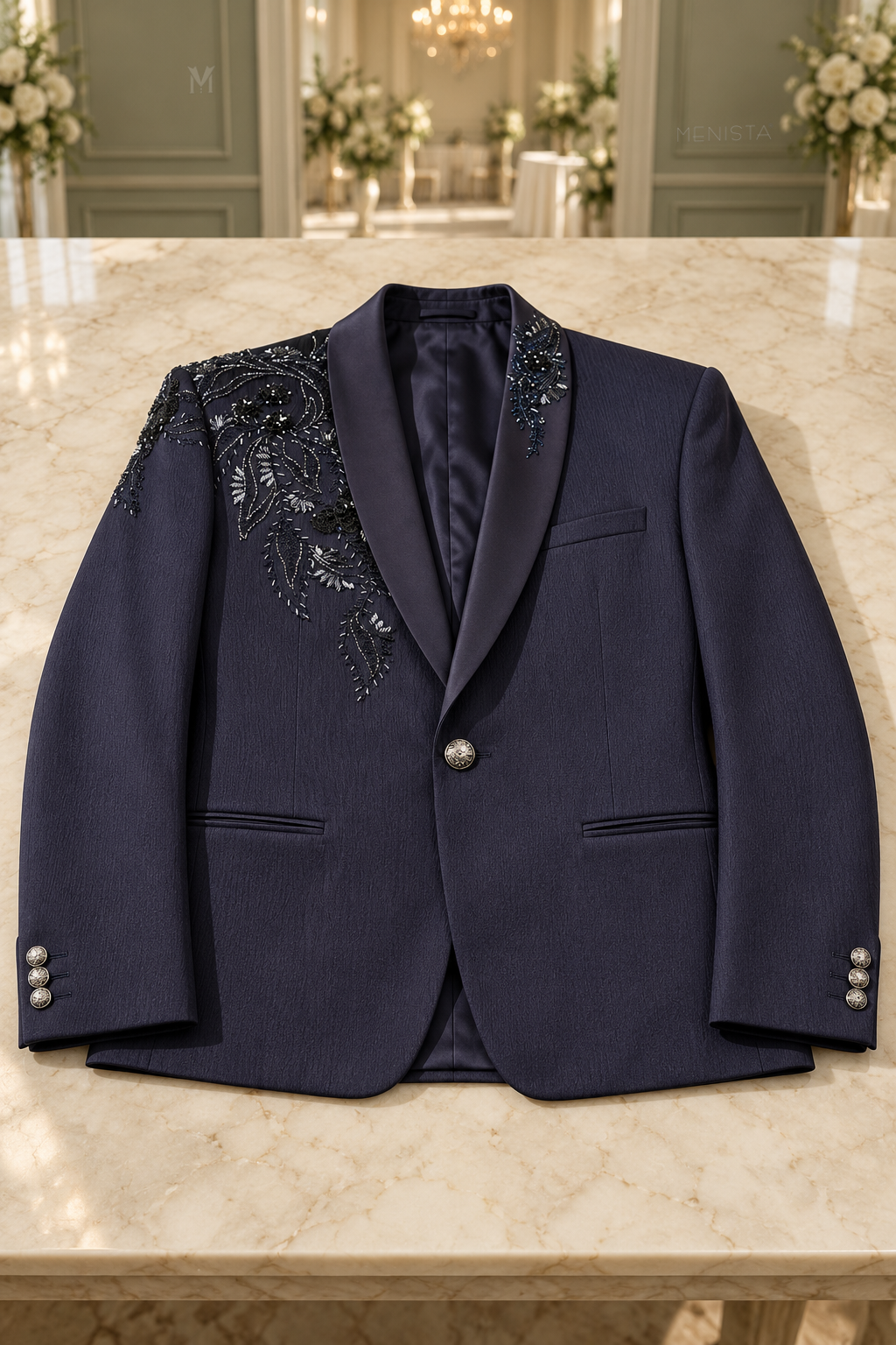 Cassian navy floral embroidered jacket laid flat on a stone tabletop, showing one front button, three cuff buttons and two jetted pockets.