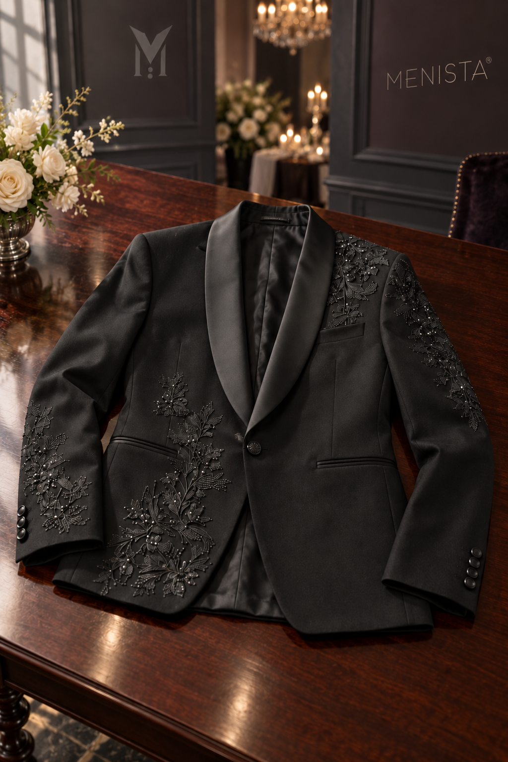 Lucien black floral embroidered jacket resting on a flat mahogany table, with one front button and jetted pockets.
